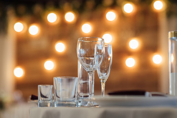 Glasses, flower fork, knife served for dinner in restaurant with cozy interior