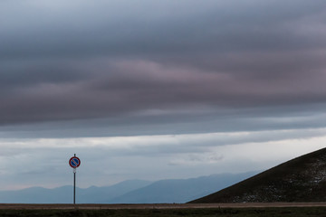 Road sign against a moody sky background with big clouds