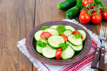 Diet salad of fresh cucumbers and tomatoes, cut into slices on wooden table