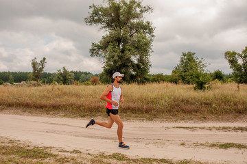 Man running outdoors with a beard in a sports uniform in nature, day, open air