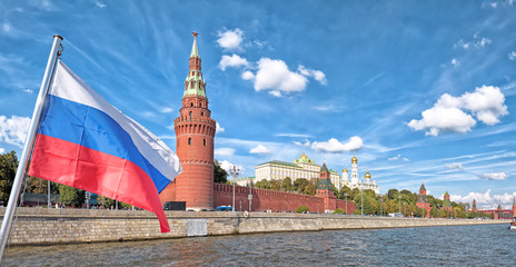 moscow city russia kremlin and russian flag state symbol architecture famous landmark background panorama wide river view of russian capital red wall and tower buildings historical town center skyline - obrazy, fototapety, plakaty