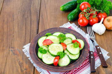 Diet salad of fresh cucumbers and tomatoes, cut into slices on wooden table