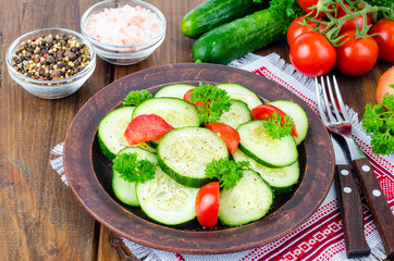 Diet salad of fresh cucumbers and tomatoes, cut into slices on wooden table