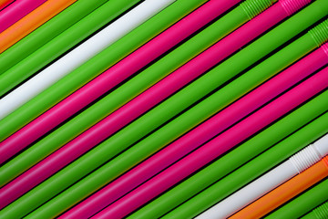 Plastic straws different colors on a dark background close up