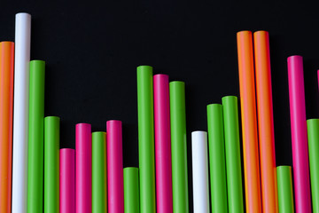 Plastic straws different colors on a dark background close up