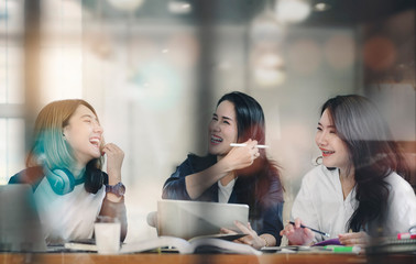 Girls having fun while working at cafe, laughing and enjoying together.