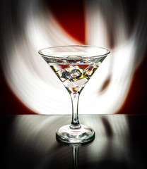 Martini glass isolated on a red background with stripes of neon light painting behind them. Light wave, play of colors, drawing with light.