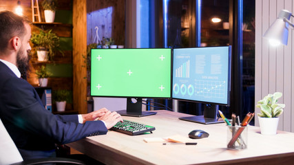 Businessman working on two monitors one of them has the green screen