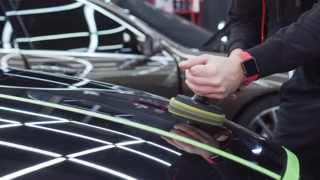 Executive worker of bus station polishes the hood of the car to a mirror shine