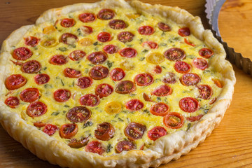 Cherry tomato tart of puff pastry tomato cheese and egg quiche out of oven on wooden table