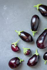Ripe eggplants of different sizes on a gray concrete background. Top view.
