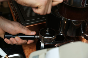 Barista pressing ground coffee with tamper in portafilter, closeup