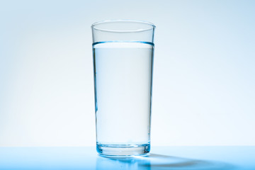 Glass of water on blue background. Refreshing drink