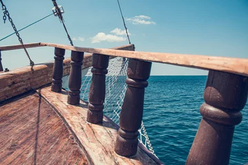  The bow of an ancient ship. Vintage ship at sea. View of the sea through the beams and the side of an old wooden ship, rapidly sailing on the sea © OleJohny
