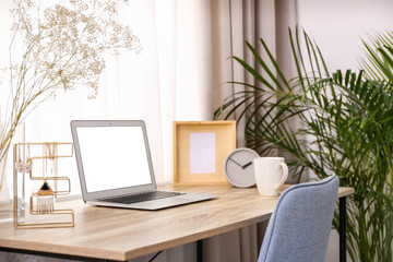 Fototapeta na wymiar Stylish workplace interior with laptop on wooden table near window