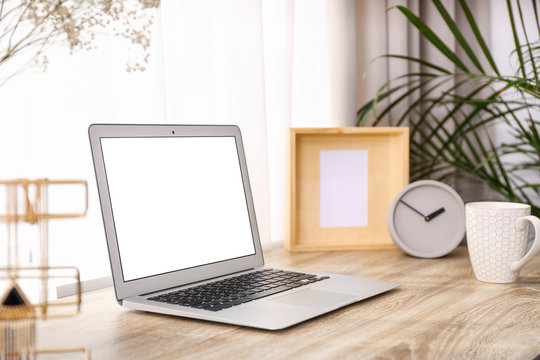 Stylish workplace interior with laptop on wooden table near window