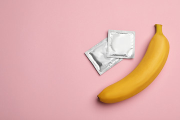 Condoms with banana and space for text on pink background, flat lay. Safe sex