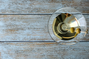 Glass of Classic Dry Martini with olives on wooden table, top view. Space for text