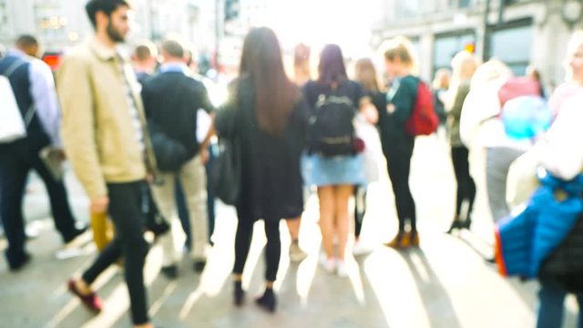 Rear view of blur defocused silhouettes of pedestrians people walking in slow motion on Oxford Circus interchange between the Bakerloo, Central and Victoria lines waiting to cross the street