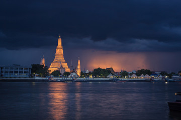 Amazing Wat Arun temple at dusk in Bangkok city, Thailand. On a monsoon evening with stormy clouds and light reflections. Beautiful south east asia culture and heritage 