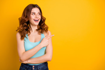 Copyspace photo of charming cute nice cheerful emotional sweet gorgeous girlfriend wearing jeans denim teal singlet while pointing away at emptiness isolated with yellow vivid color background