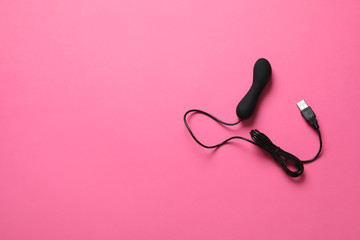 Black electric powered vibrator on pink background, top view with space for text. Sex toy