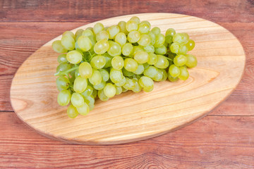 White grapes cluster on the oval wooden serving board