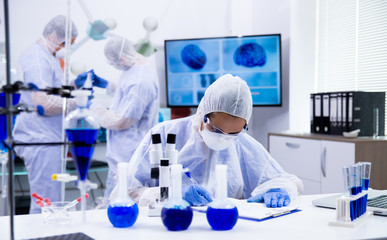 Female scientist with microscope near and smoking blue solution