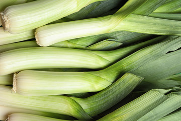 Fresh raw leeks as background, closeup. Ripe onion