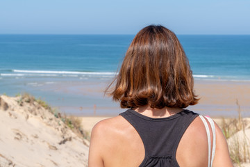 closeup back woman standing in beach dune look sea beach water