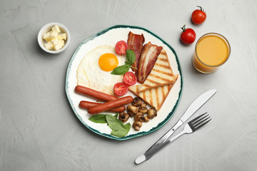 Traditional English breakfast with fried egg served on grey table, flat lay
