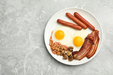 Traditional English breakfast with fried eggs on light grey marble table, top view. Space for text