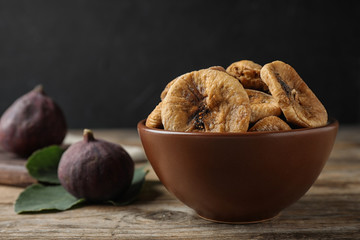 Bowl of tasty dried figs on wooden table. Space for text
