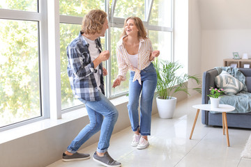 Happy young couple dancing at home