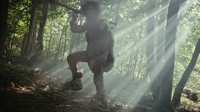 Portrait of Primeval Caveman Wearing Animal Skin and Fur Hunting with a Stone Tipped Spear in the Prehistoric Forest. Primitive Neanderthal Hunter Ready to Throw Spear in the Jungle
