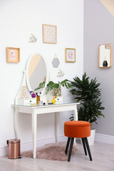 Stylish room interior with modern dressing table near light wall