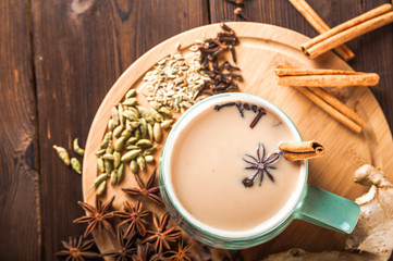Details of still life in the home interior living room. Beautiful Cup of tea with milk, star anise, cinnamon on a wooden background. Cozy autumn-winter concept. Masala is a traditional hot spicy drink