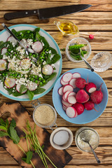 Woman photographs a table with ingredients for Summer Fresh Salad with radishes, feta, feces and mint leaves.