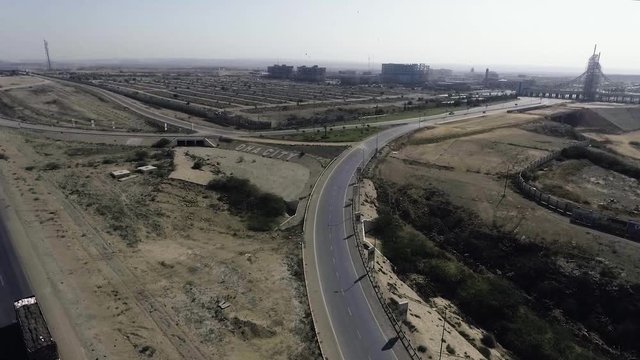 An aerial slow mo view of a highway and city, The heavy trawlers and cars are moving on the highway, an interchange is connecting.