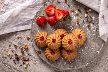 Biscuit with strawberry filling. Crispy and crumbly delicious cookies with natural ingredients: flour, nuts, seeds, pieces of chocolate, cocoa, fruit jams. Spring Flower Still Life
