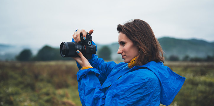 photographer tourist girl in blue raincoat hold in hands photo camera take photography foggy mountain, traveler shooting autumn nature, video click on camera technology, landscape vacation concept