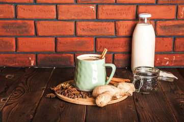 Details of still life in the home interior living room. Beautiful Cup of tea with milk, star anise, cinnamon on a wooden background. Cozy autumn-winter concept. Masala is a traditional hot spicy drink