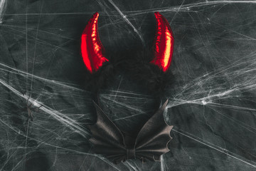 Red demonic horns for Halloween costume or masquerade on dark background with white spider web