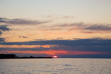 Beautiful sunset on a lake in the mountains. Kyrgyzstan, Issyk-Kul Lake. Bright sky, background in warm colors.
