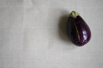 Trendy ugly organic eggplant on grey table, with copy space