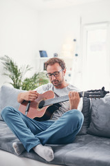 Man playing acoustic guitar in the living room.