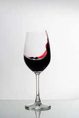 Red wine splashing up the side of a wineglass