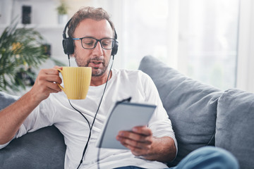 Man listening to music and using tablet in the living room.