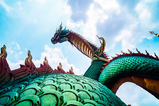 Beautiful green naga or serpent statue with blue sky and clouds background in thailand,
