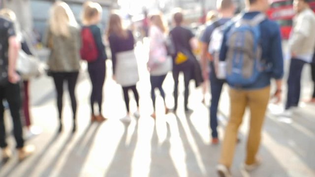 Cinematic slow motion defocused silhouettes of pedestrians people walking on Oxford Circus interchange between the Bakerloo, Central and Victoria lines sunny evening lens flare shadows